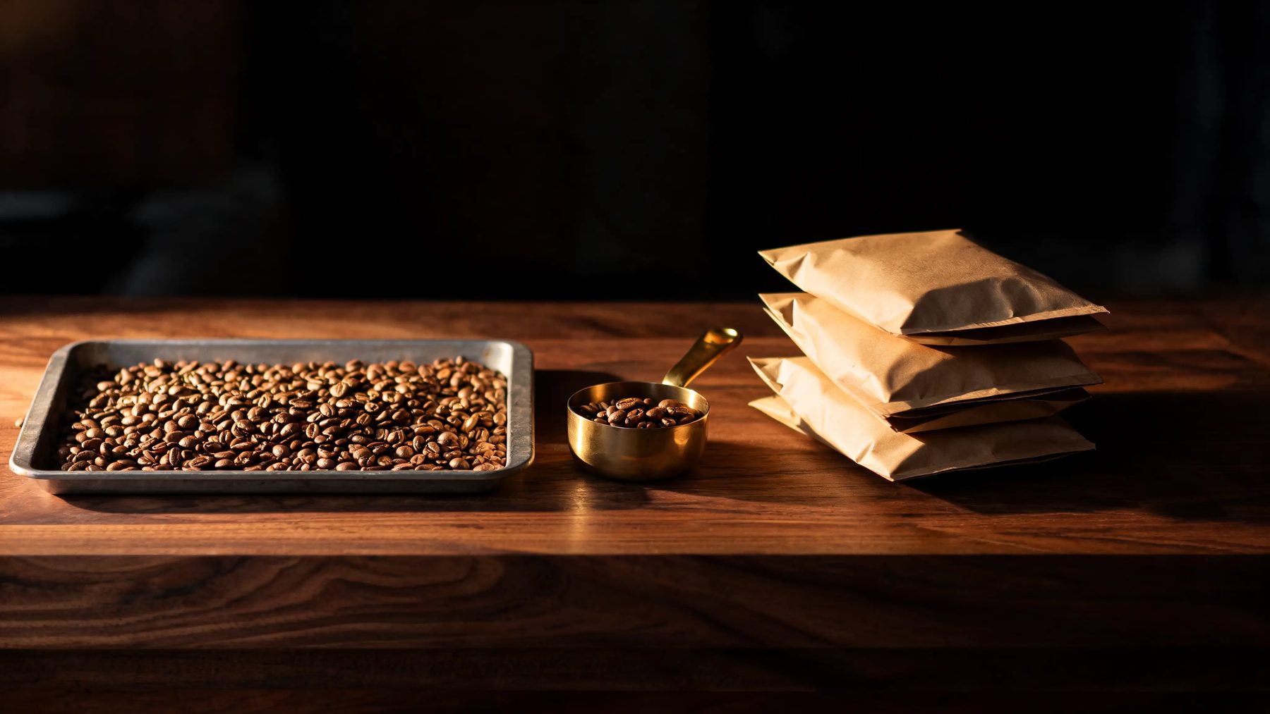 Roastery bench with a cooling tray of fresh beans and stacked kraft bags